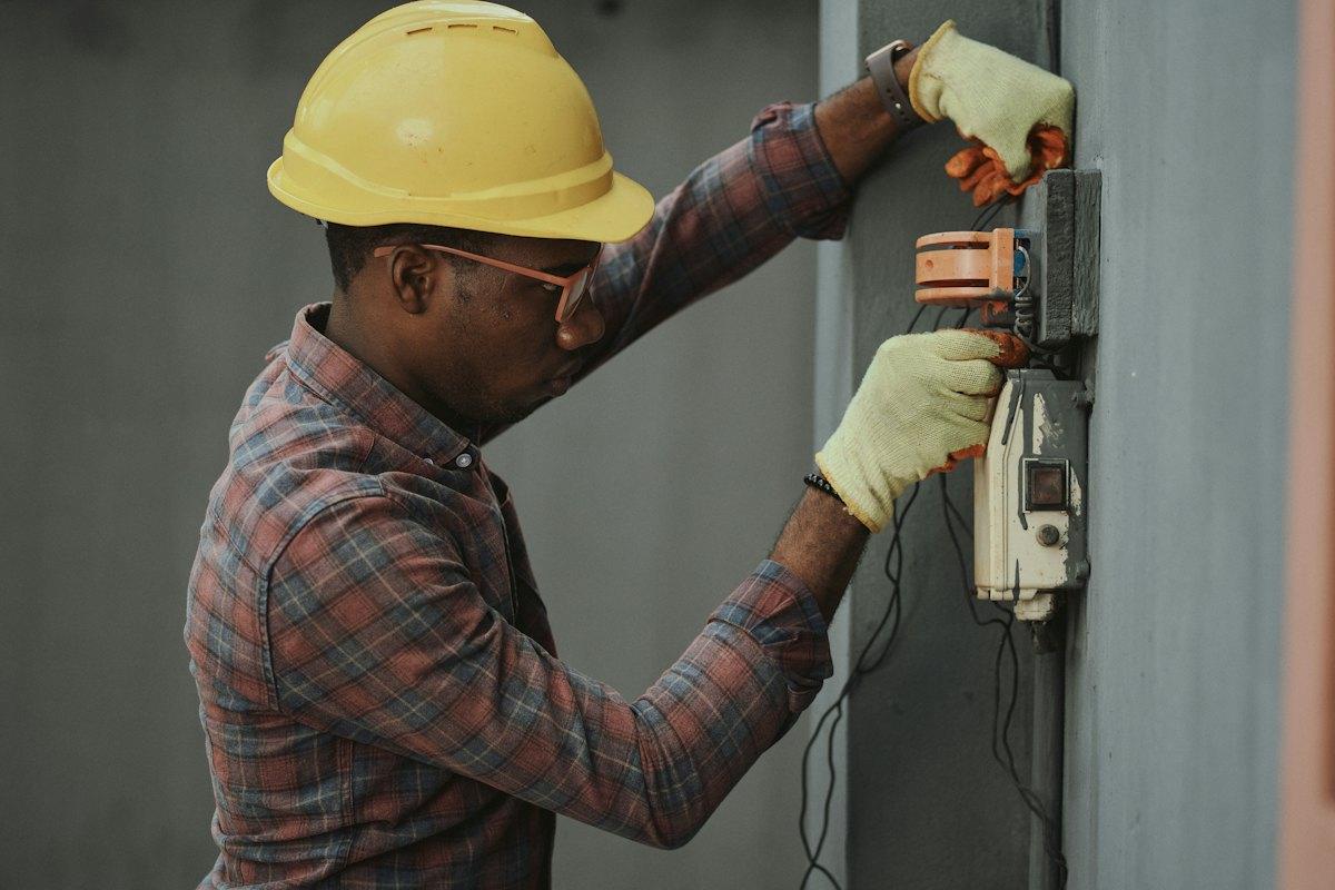Technician in a hard hat checking electrical equipment